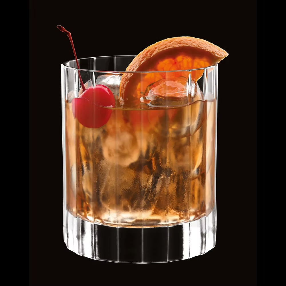 Old fashioned cocktail in a clear glass tumbler with cherry and orange.
