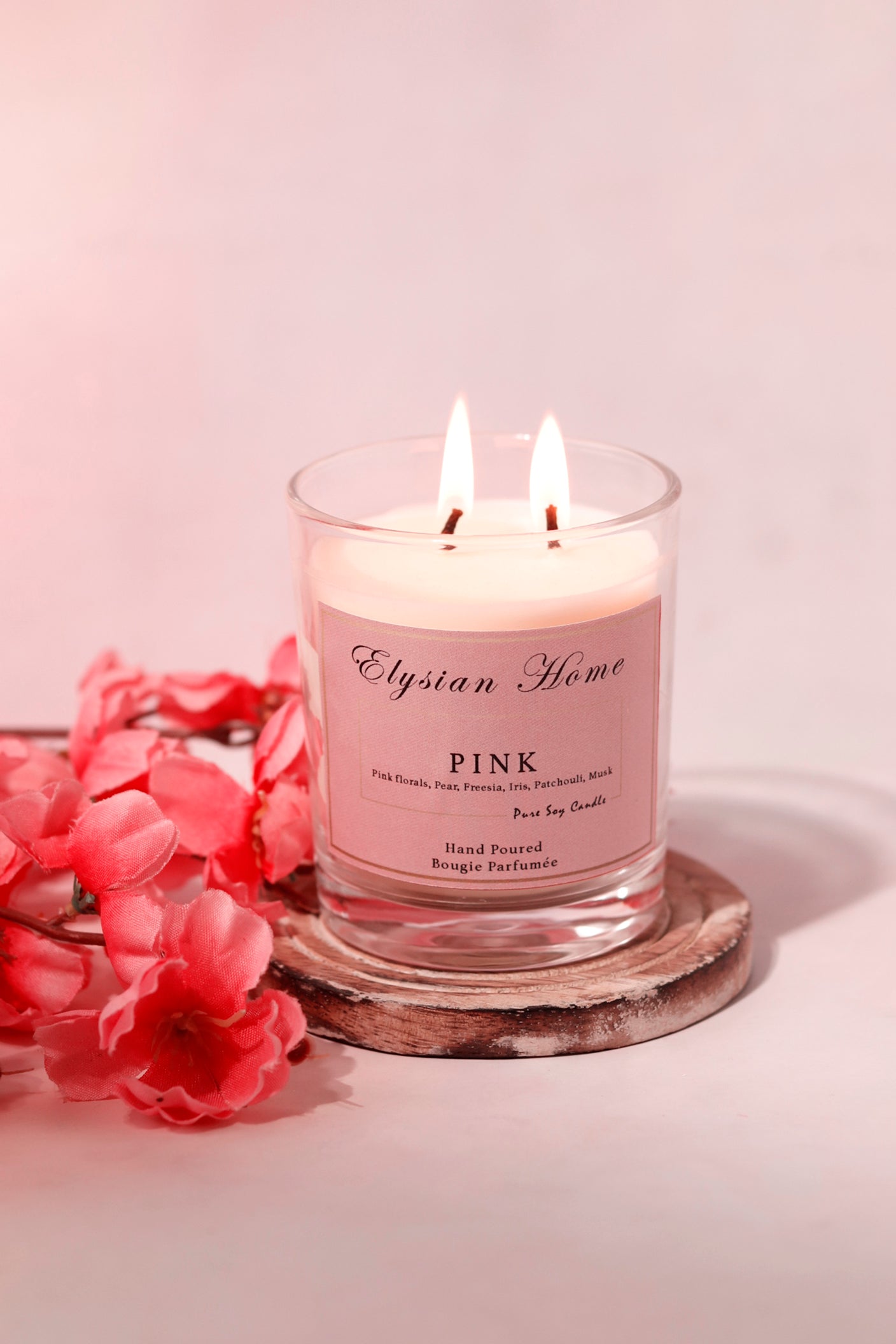 Elysian Home candle with pink florals scent on a wooden coaster.