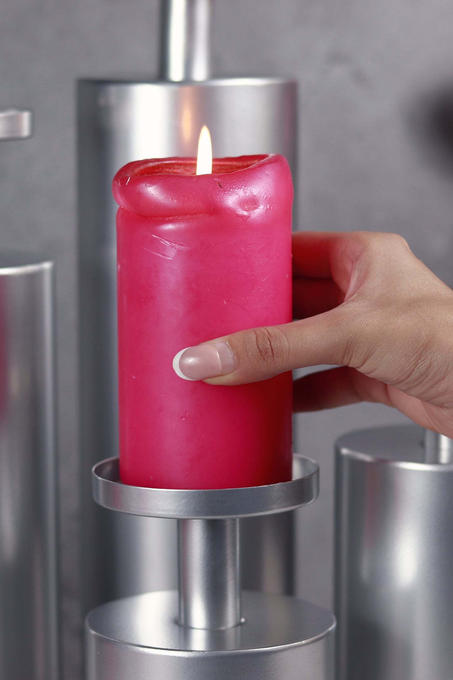 Lit candle on chrome Magnolia candle stand.