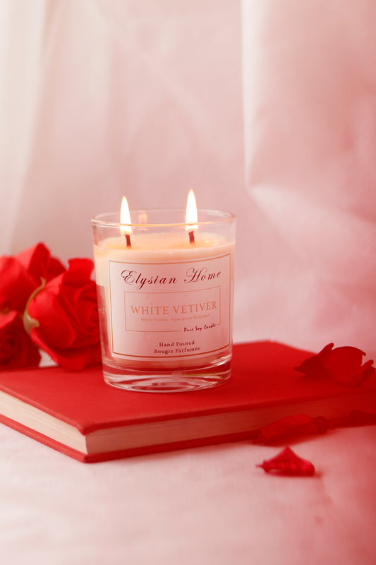 Burning White Vetiver scented candle in glass, on red book.