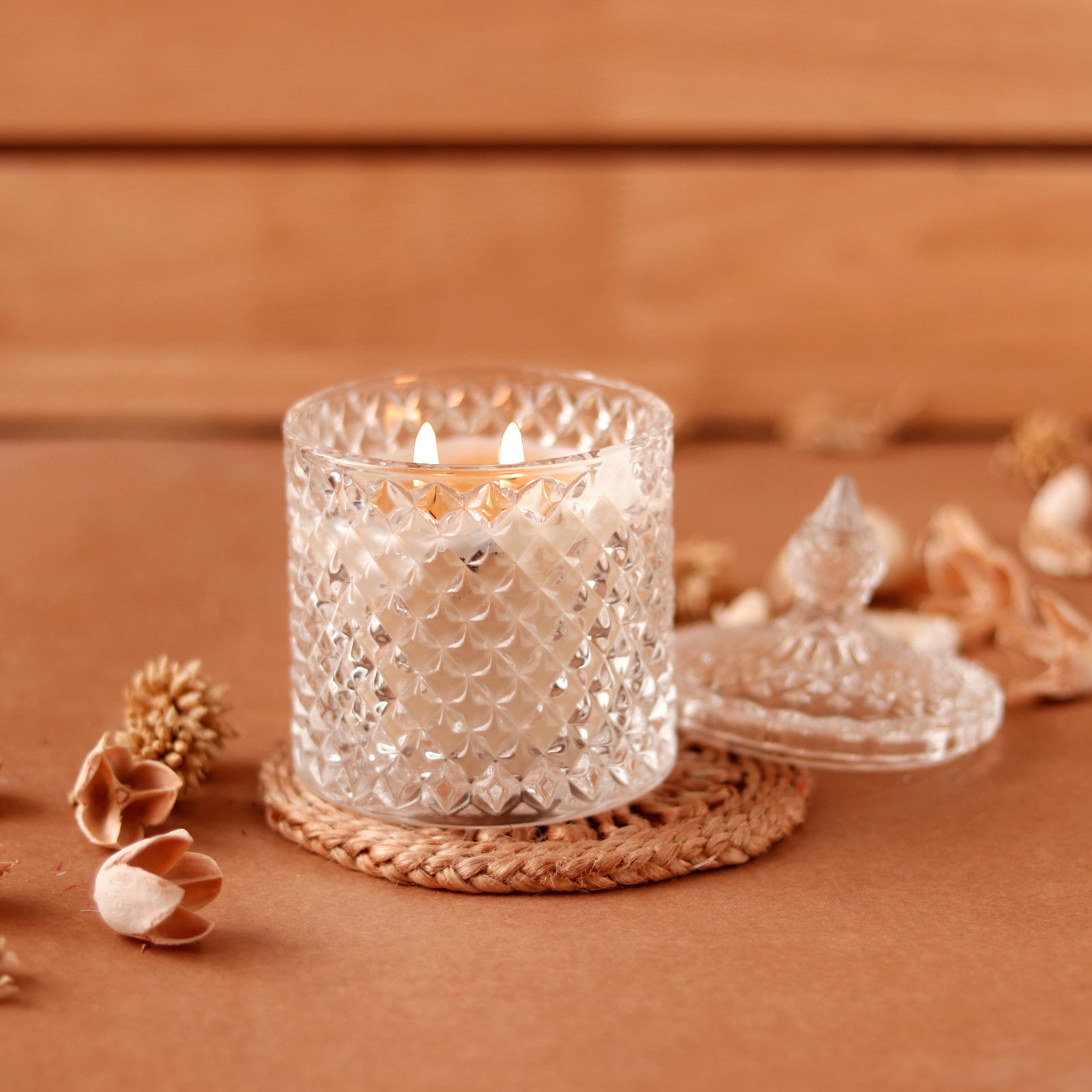 Lit crystal candle with lid on woven coaster, elegant design.
