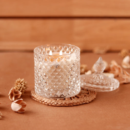 Lit crystal candle with lid on woven coaster, elegant design.