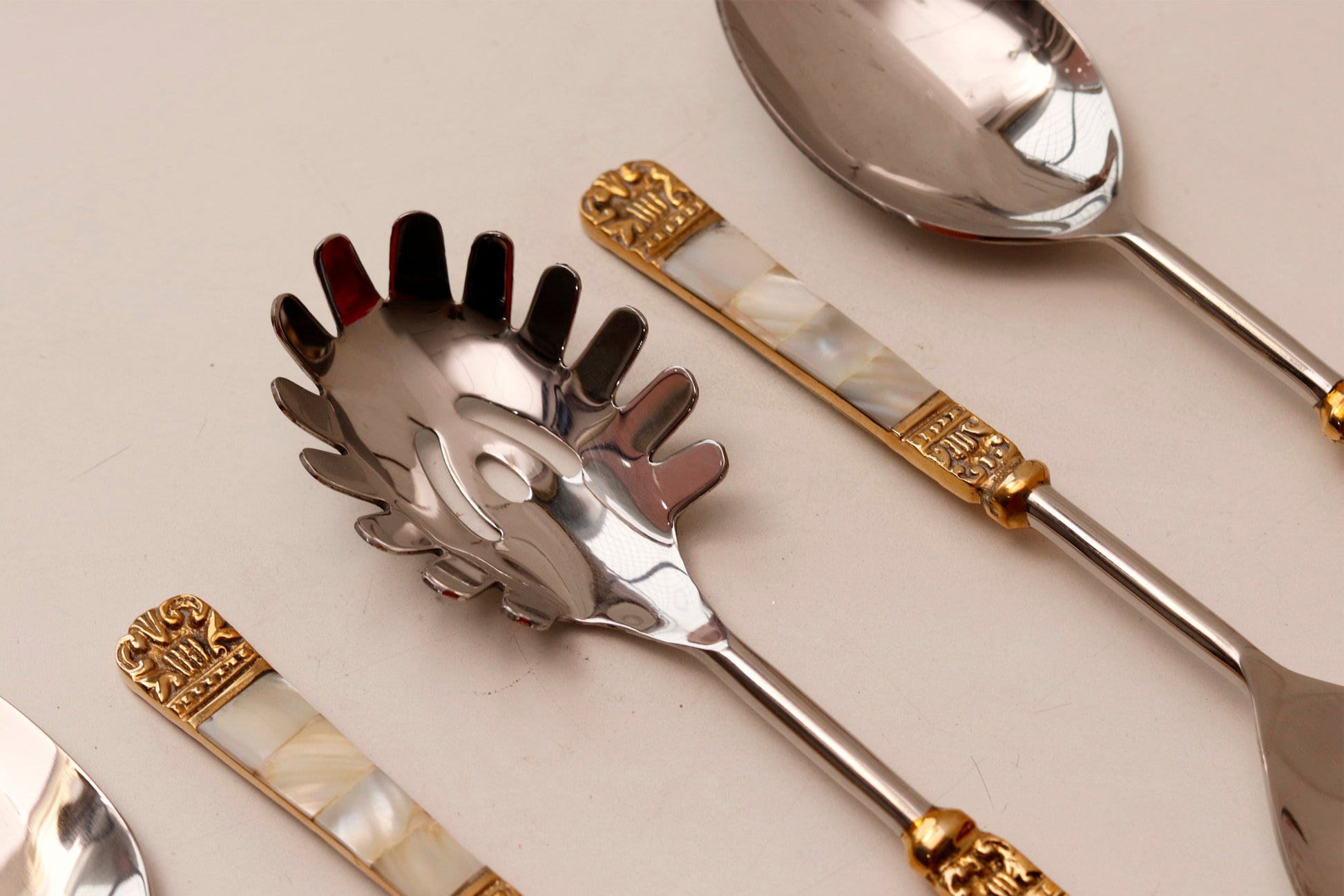 Serving spoons set with mother of pearl inlaid handles and gold accent.