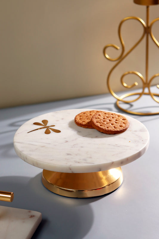 White marble cake stand with golden dragonfly imprint and base.