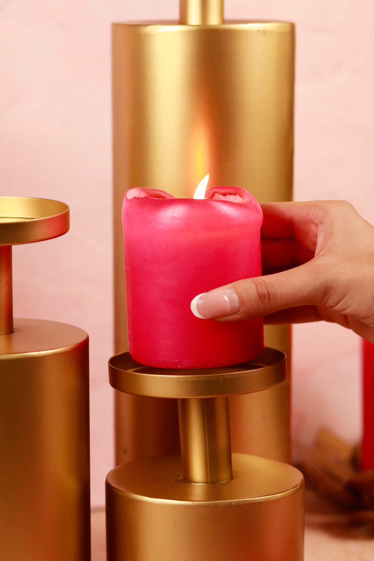 Lit candle on gold stand from the Magnolia candle stand set.