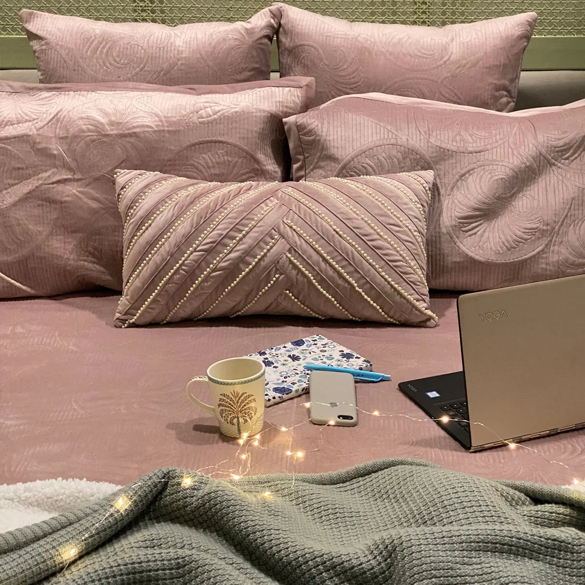 Onion pink velvet bedspread with decorative pillows.
