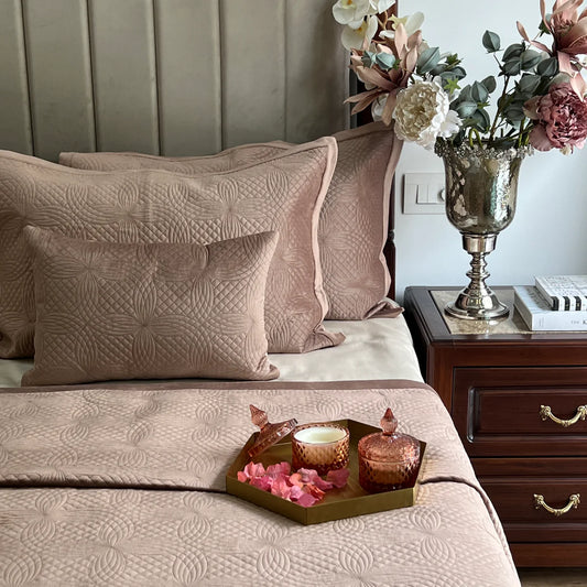 Elegant buff velvet bedspread with geometric quilt pattern and pillow shams.