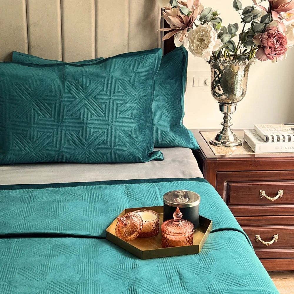 Emerald green velvet bedspread with geometric pattern and matching velvet pillows.