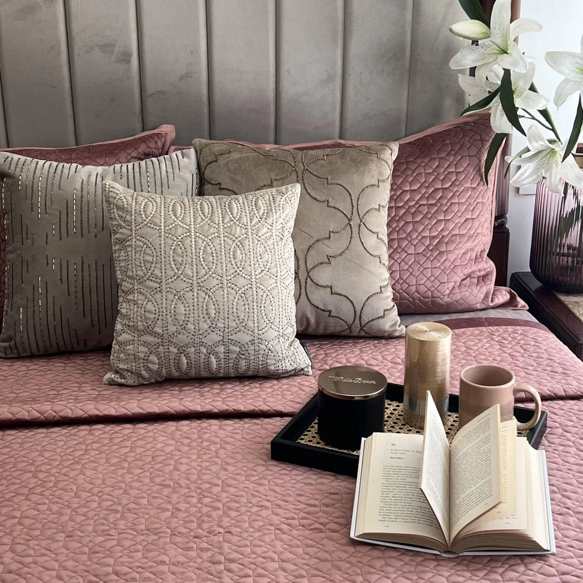 Blush velvet bedspread with quilted pattern and decorative pillows.