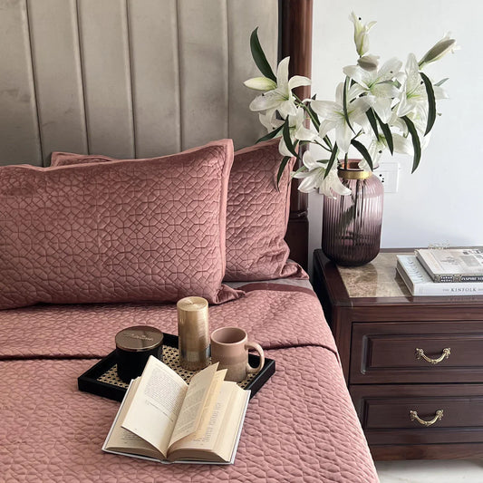 Blush velvet bedspread with a geometric quilted pattern design.