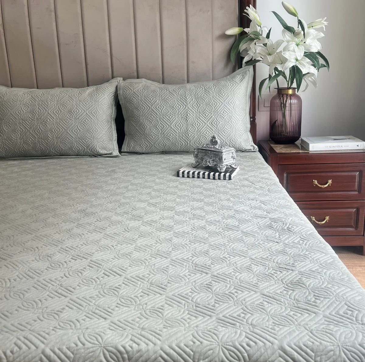 Sage green cotton bedspread with reversible geometric pattern and matching pillows.