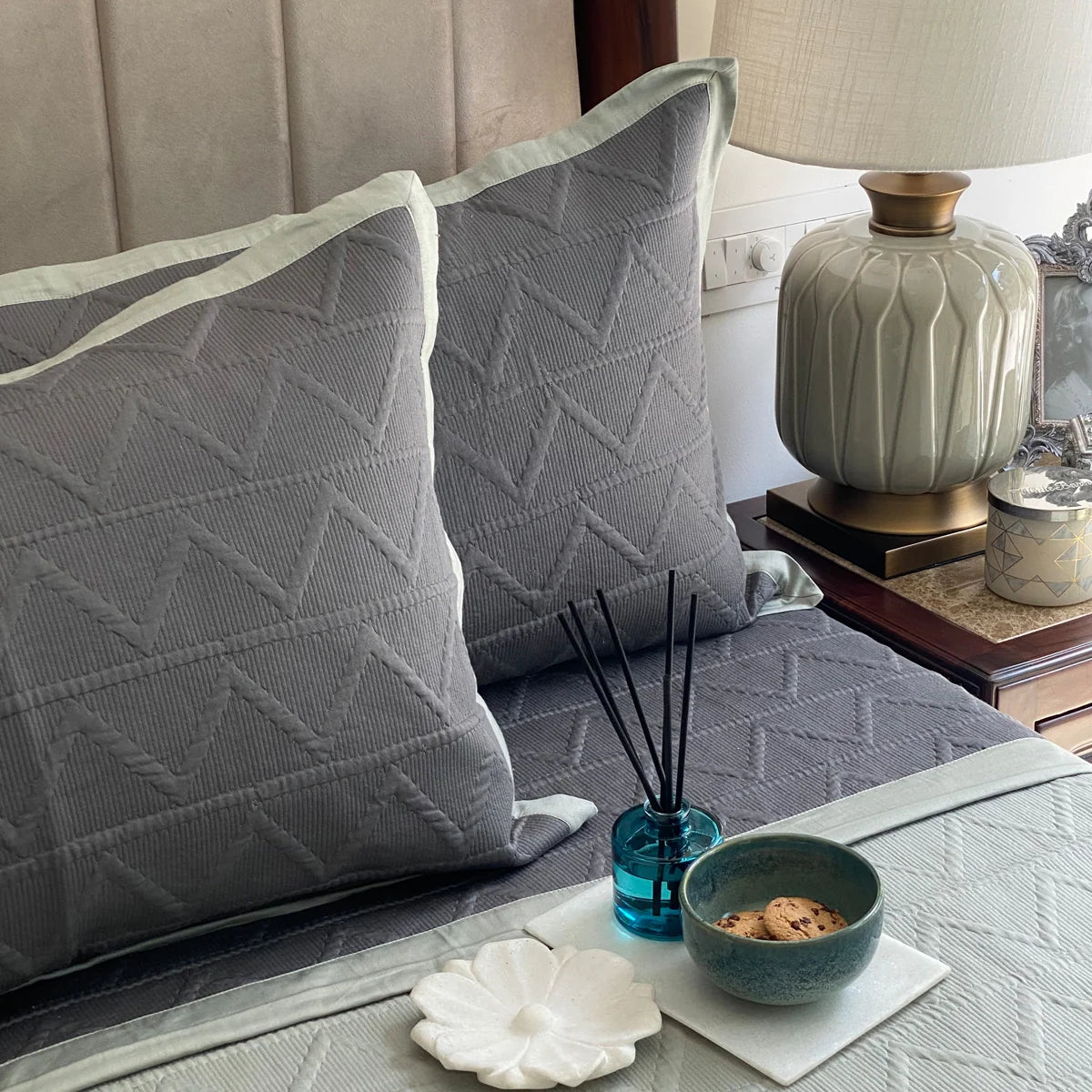 Dark green cotton bedspread with geometric pattern and sage color pillow shams.