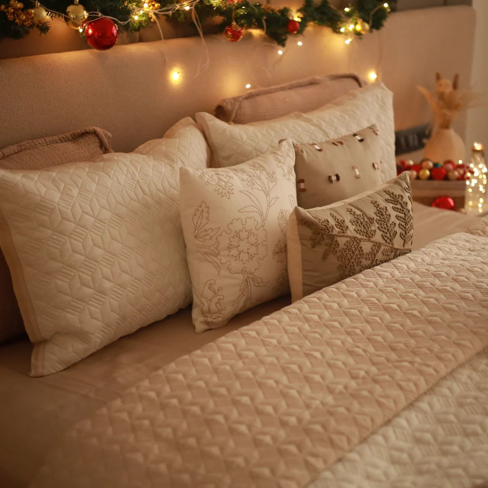 Beige cotton bedspread with ivory pillows, floral pattern.