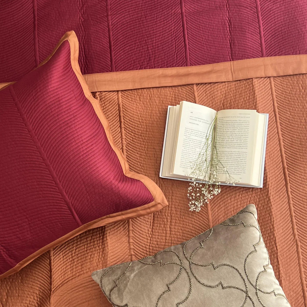 Close-up of a Rosette cotton bedspread in maroon and rust reversible pattern.