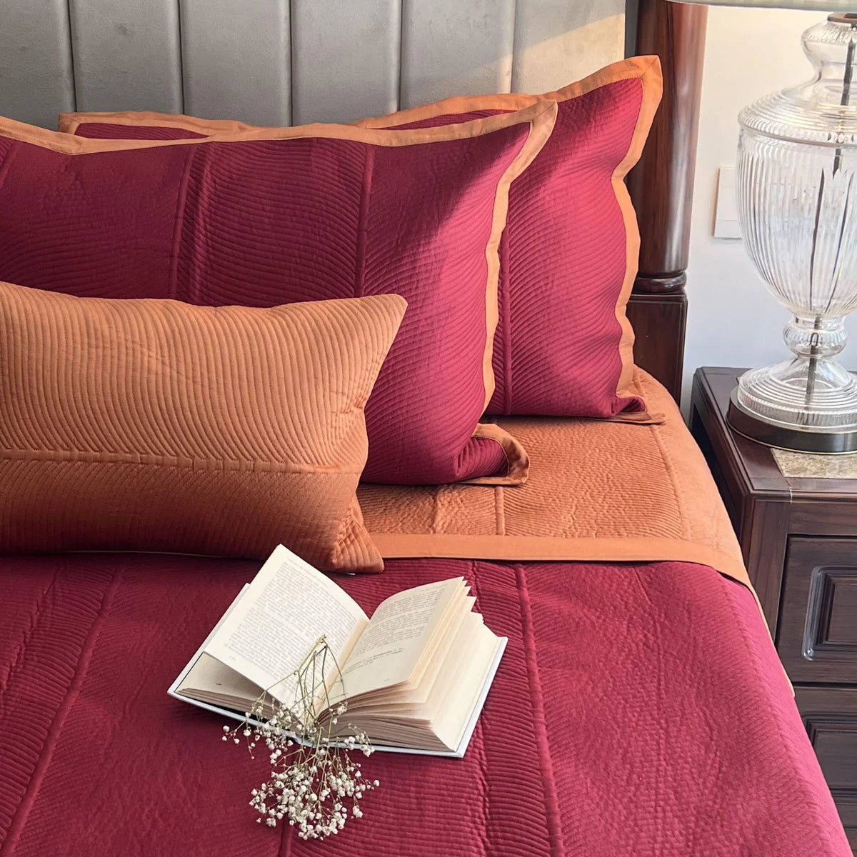 Rosette pattern cotton reversible bedspread in maroon and rust.