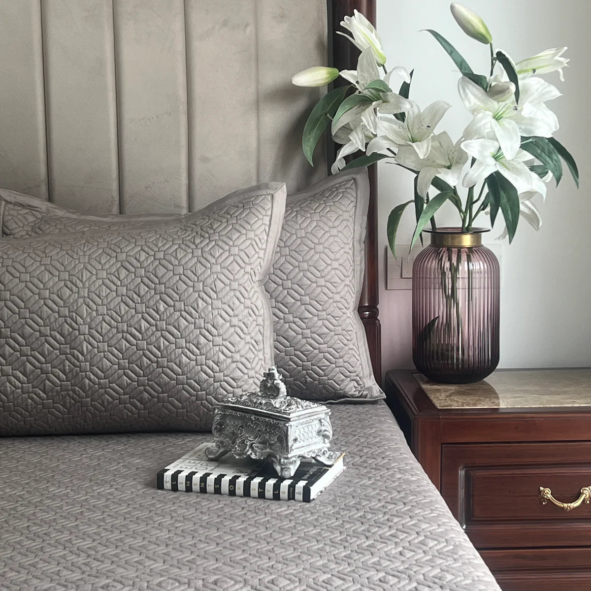Olive grey cotton bedspread with geometric pattern and matching pillows on bed.
