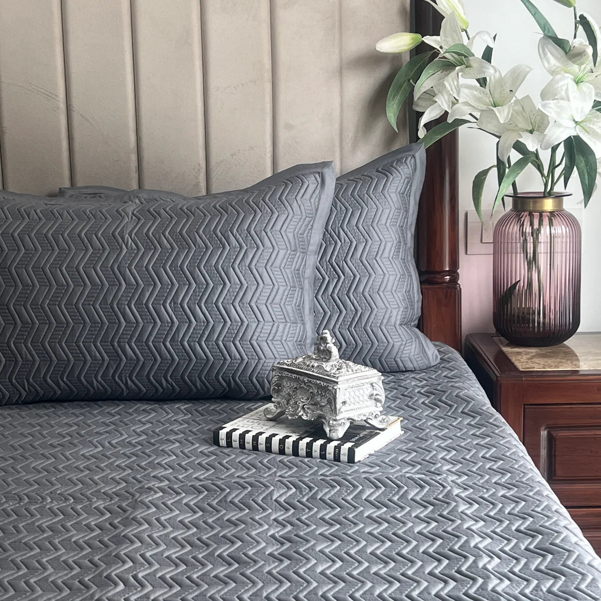 Dark grey cotton reversible bedspread with a quilted zig-zag pattern.