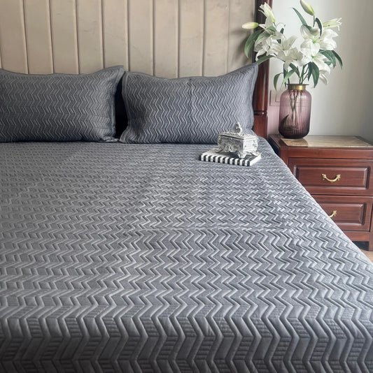 Dark grey cotton reversible bedspread with geometric pattern.