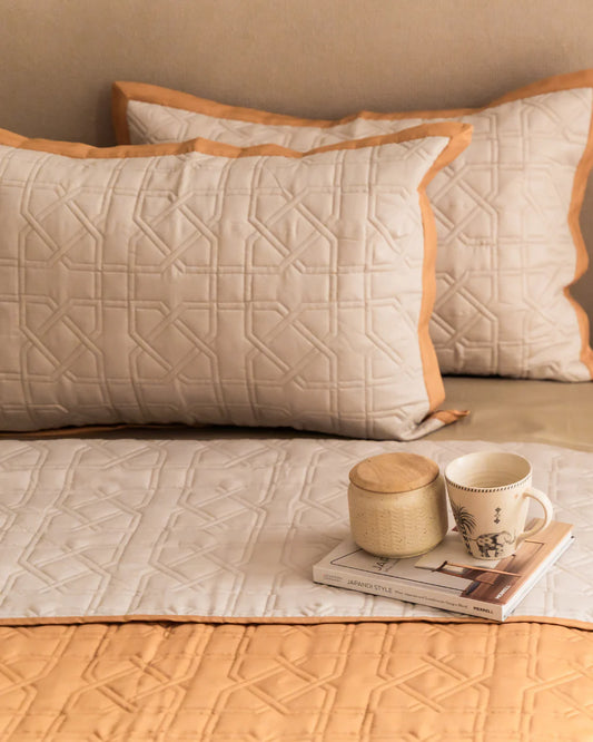 Ivory quilted bedspread with honey mustard trim and geometric pattern.