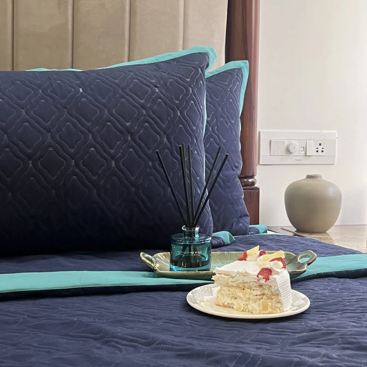 Navy turquoise quilted bedspread with geometric pattern.