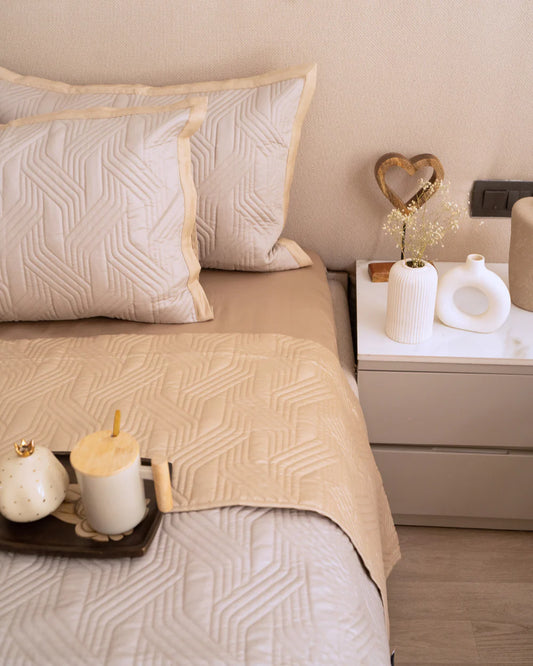 Sand and beige magnolia reversible bedspread with a quilted design.