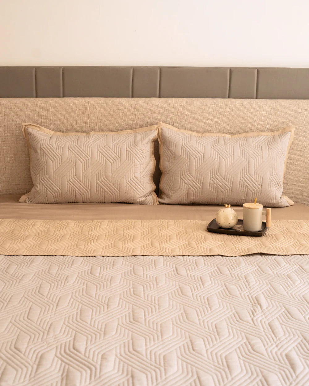Beige magnolia reversible bedspread with quilted pattern and shams.