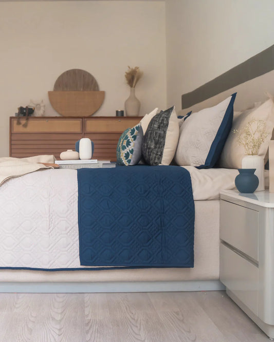 Quilted navy and ivory reversible bedspread on a made bed.