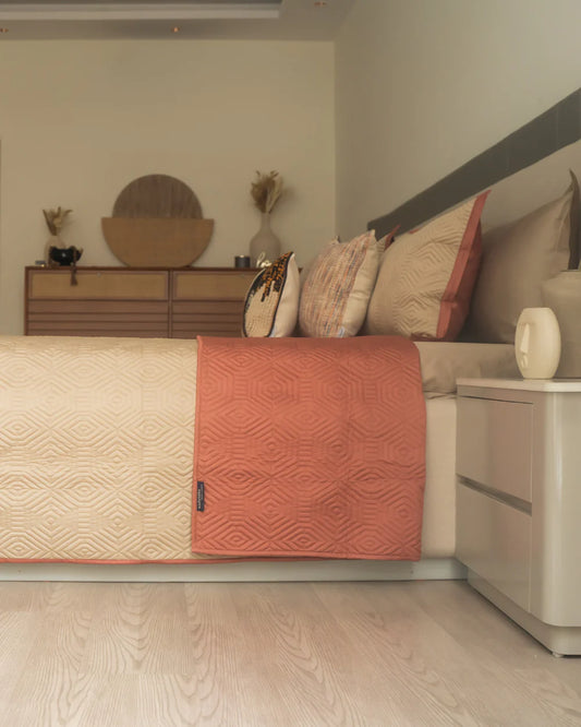 Quilted reversible bedspread in sand and terracotta colors.