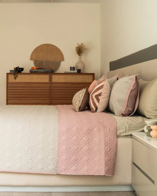 Beige and rose reversible bedspread with quilted pattern on display.