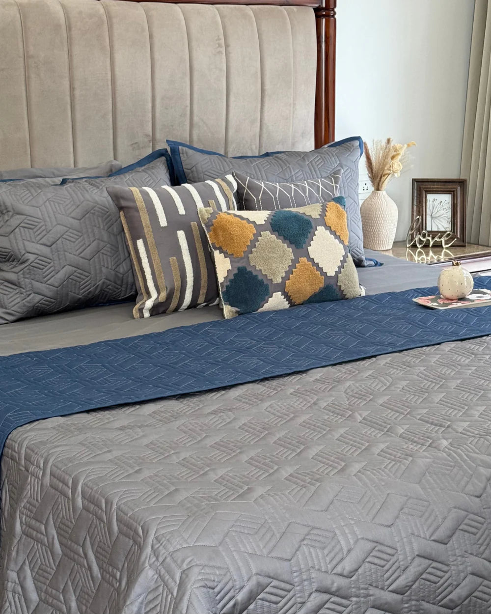 Quilted navy and grey reversible bedspread with pillows.