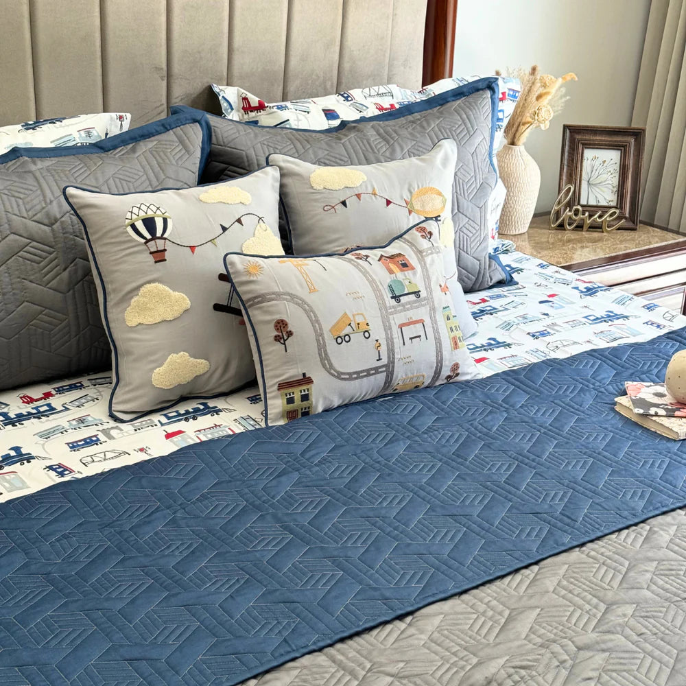 Quilted navy and grey bedspread with transportation themed pillows