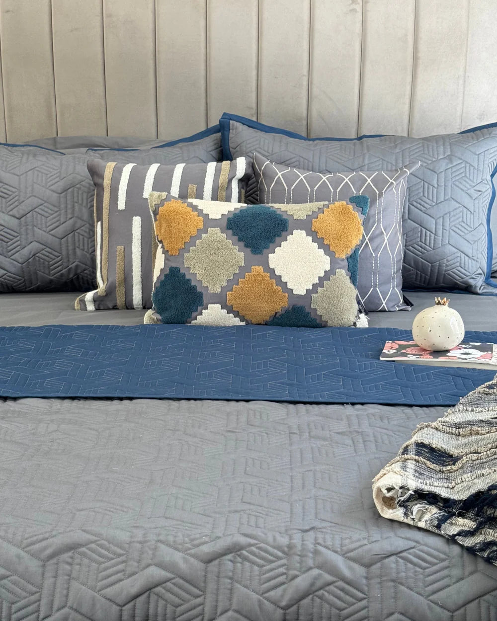 Quilted navy and dark grey reversible bedspread with matching cushions.