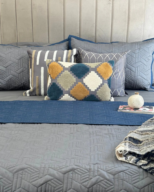Quilted navy and dark grey reversible bedspread with matching cushions.