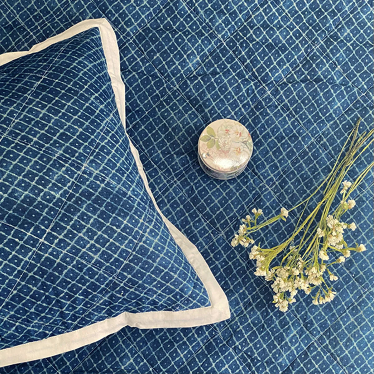 Indigo bedspread with diamond pattern and pillow.