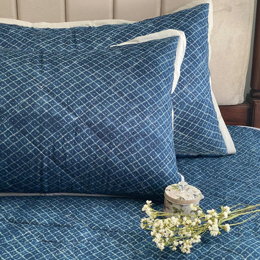 Indigo bedspread with diamond pattern and matching pillow covers.