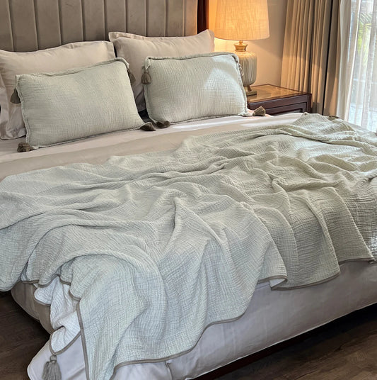 Sage woven bedspread with tassel details and matching pillows.