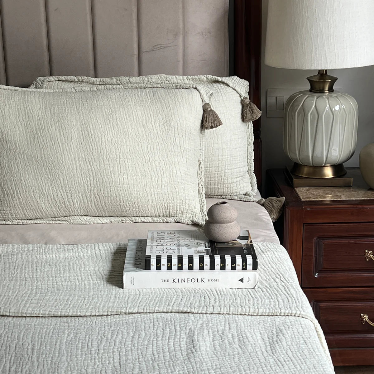Sage woven bedspread with textured pillows and tassel detail.