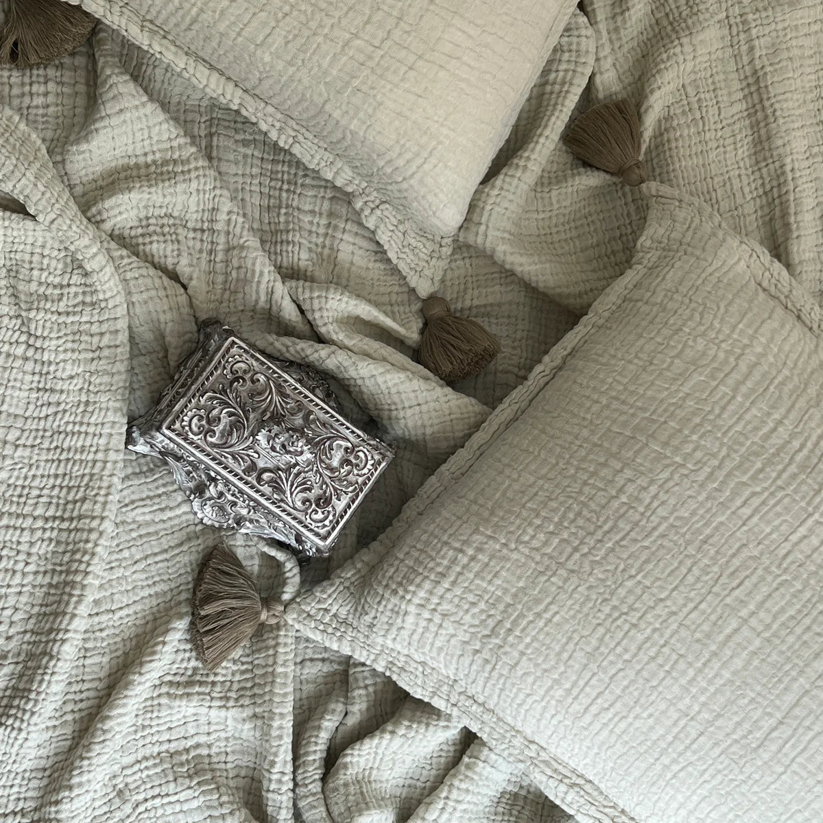 Sage woven bedspread with crinkled texture and tassel details.