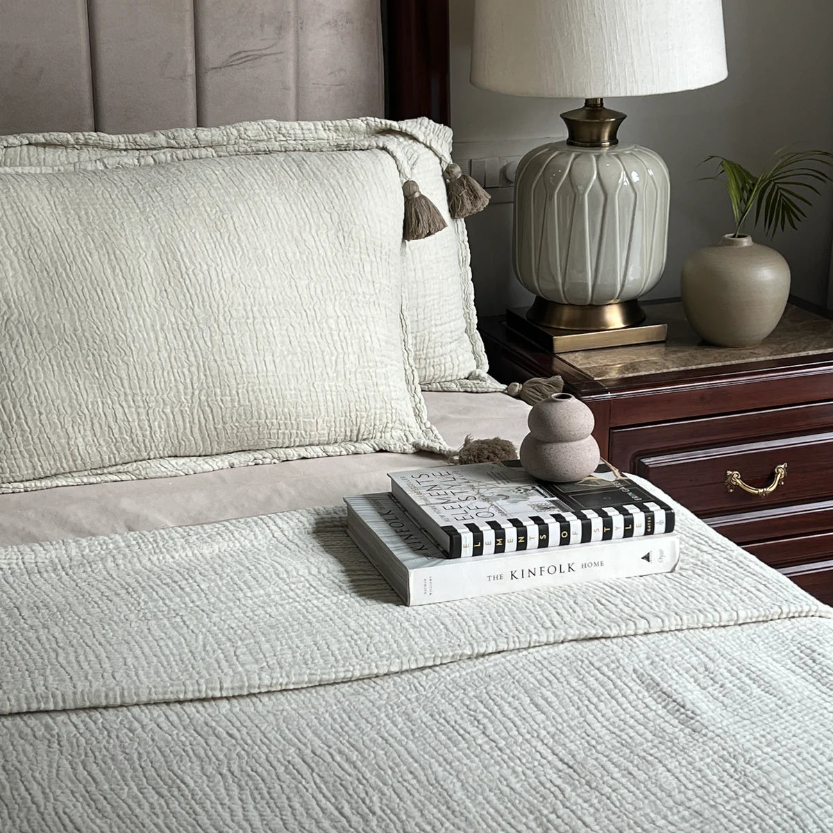 Sage woven bedspread with textured pillow and tassel detail.