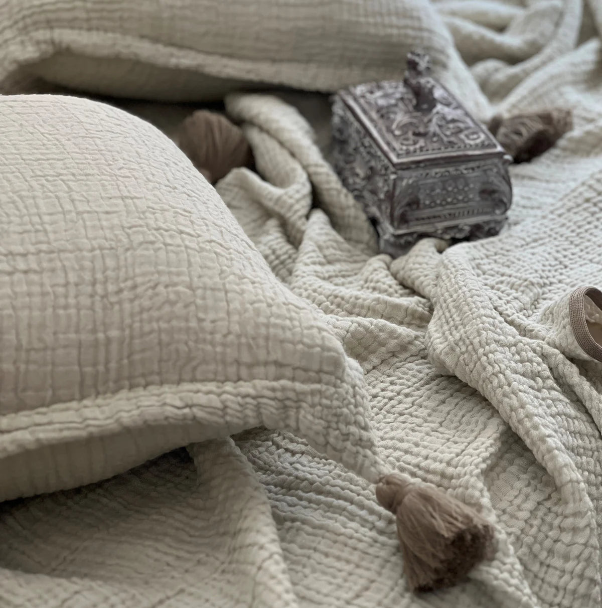 Textured woven bedspread in sage with decorative tassels.