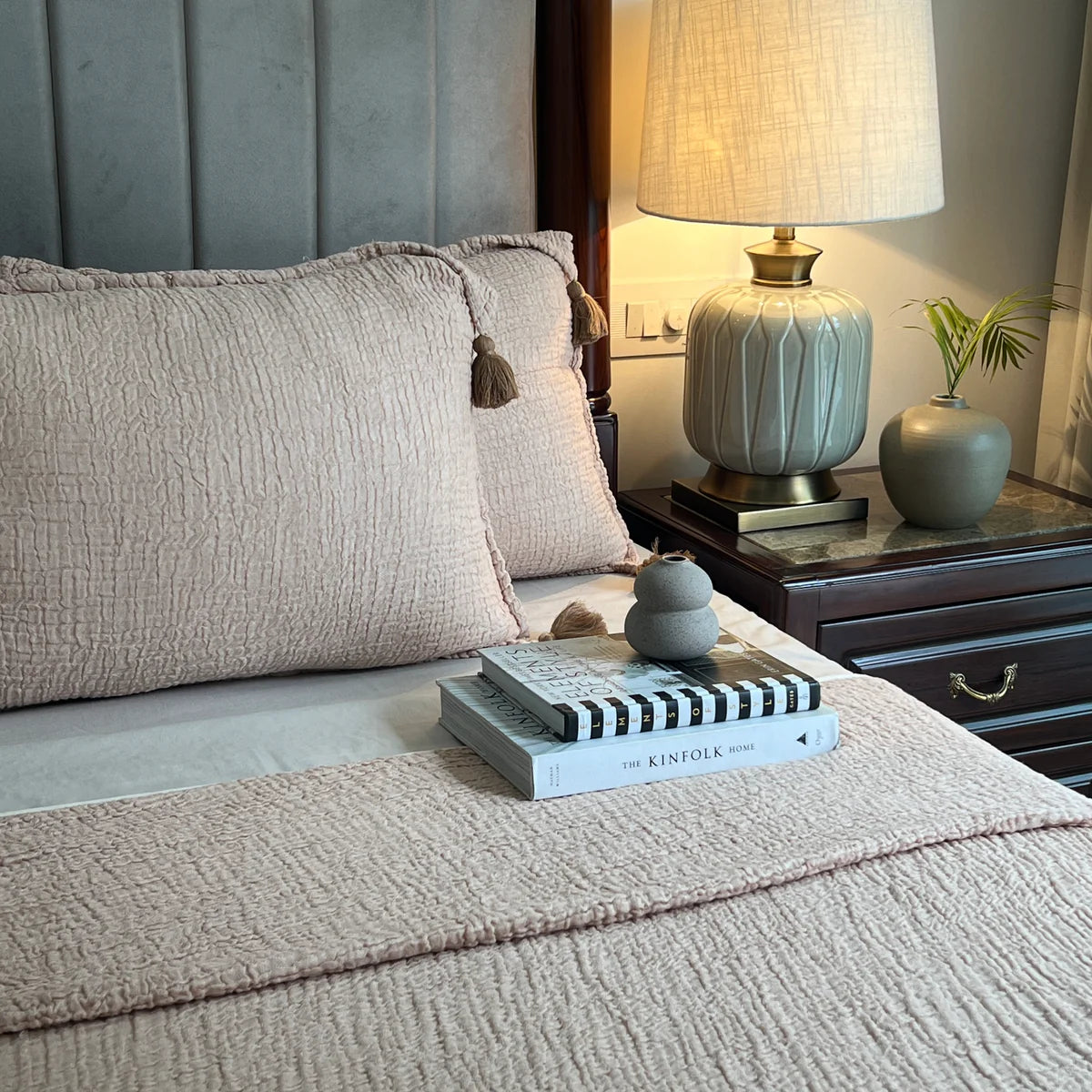 Woven sage bedspread with textured pillow shams and tassels.