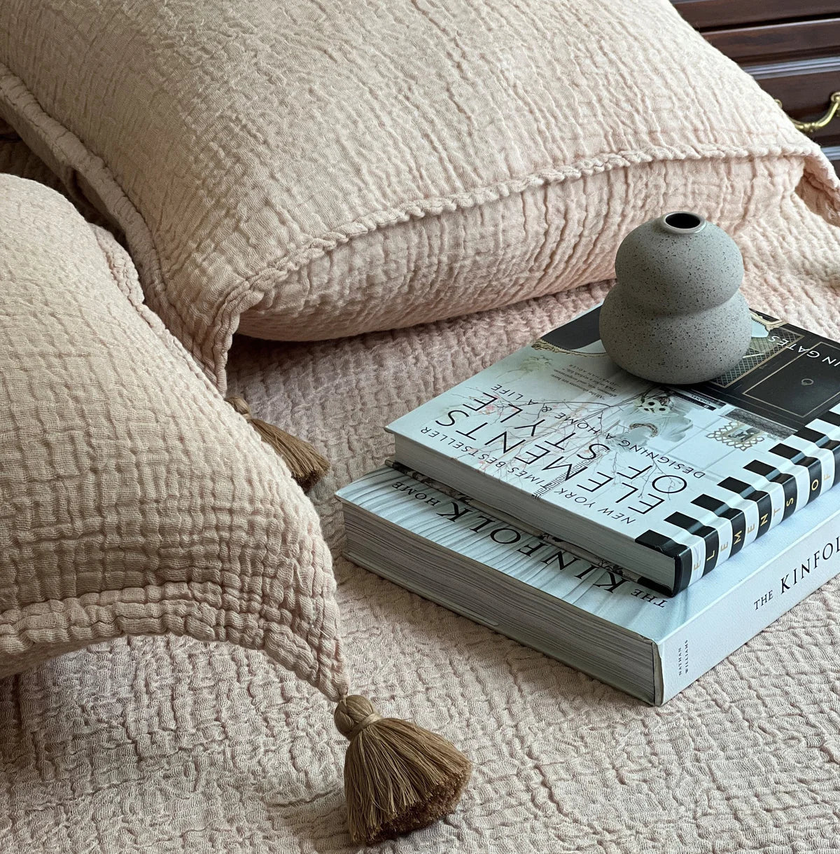 Textured woven bedspread with tassel pillows on a styled sage bed.