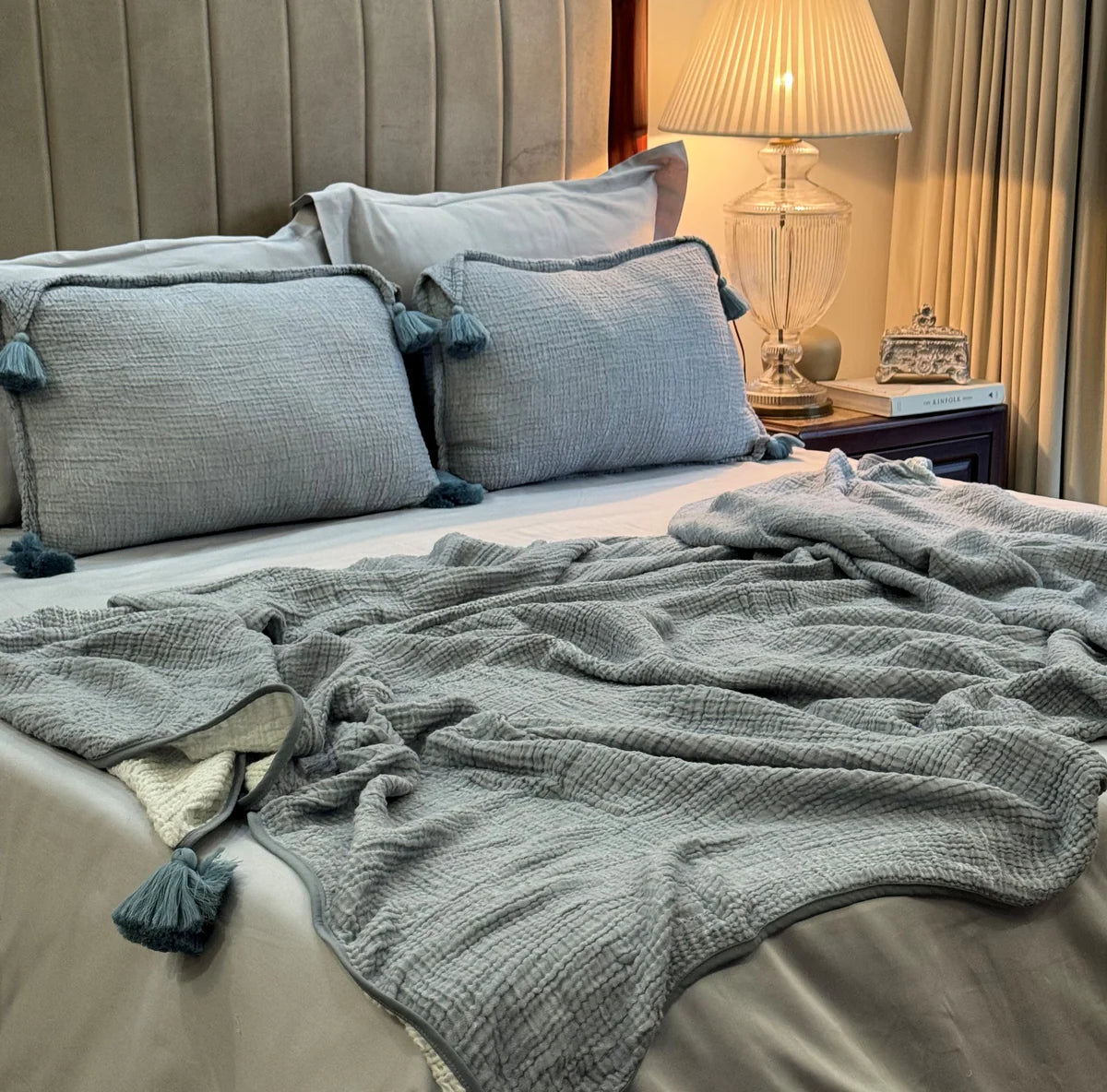 Indigo woven bedspread with textured details and tassels on a cozy bed setting.