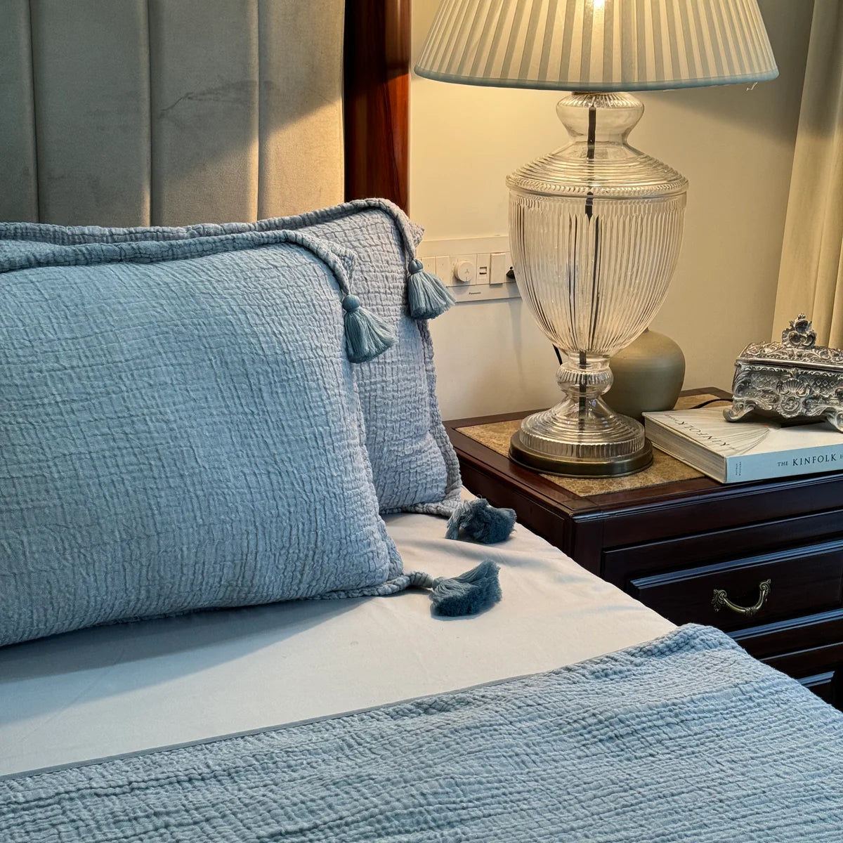 Indigo woven bedspread with tassel pillow shams on bed.