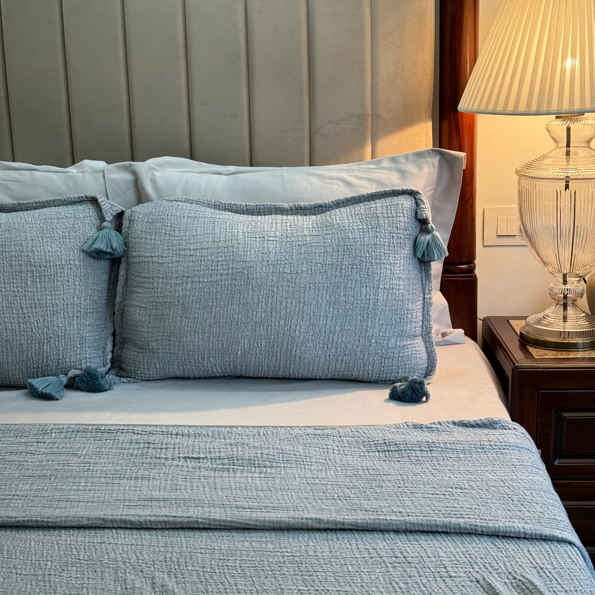 Indigo woven bedspread with tassel pillows displayed on bed.