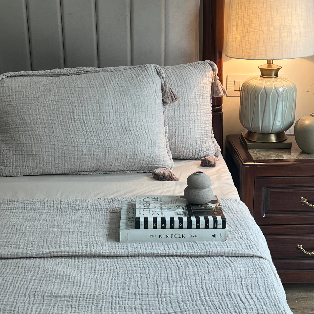 Greige woven bedspread with textured design and tassel pillow shams.