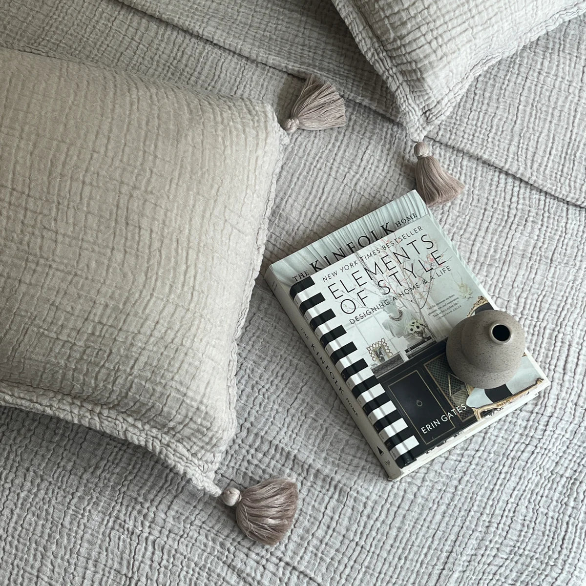 Greige woven bedspread with tassel pillows on a cozy bed.
