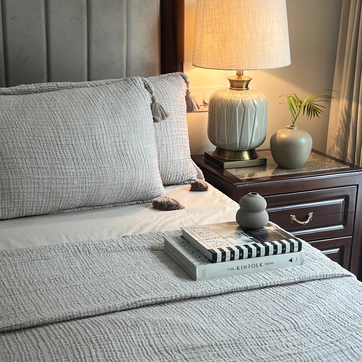 Greige woven bedspread with tassels on a cozy bed.