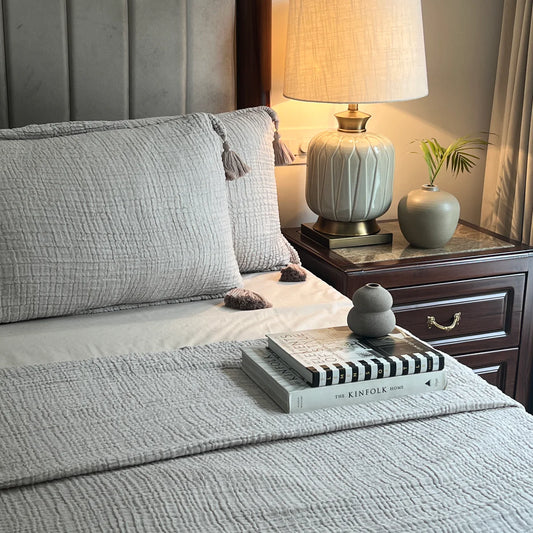 Greige woven bedspread with tassels on a cozy bed.