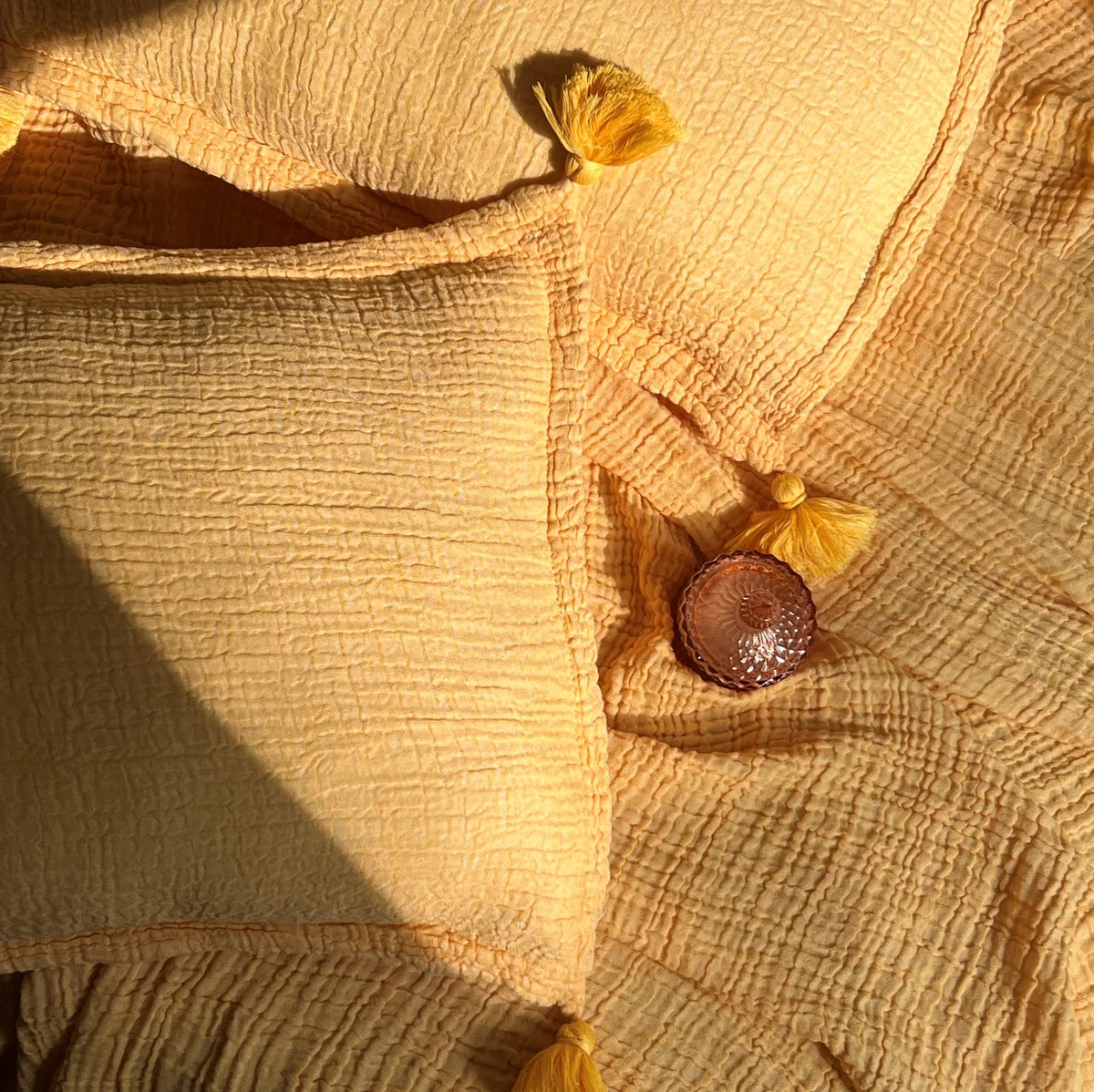 Buttercup yellow woven bedspread with tassels and matching pillow.